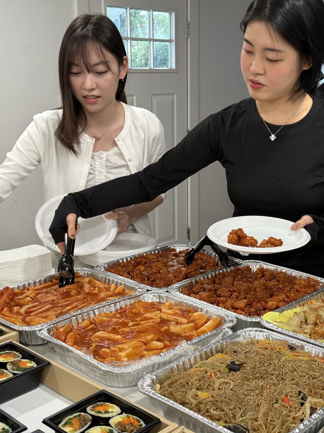 Students plating tteokbokki and japchae