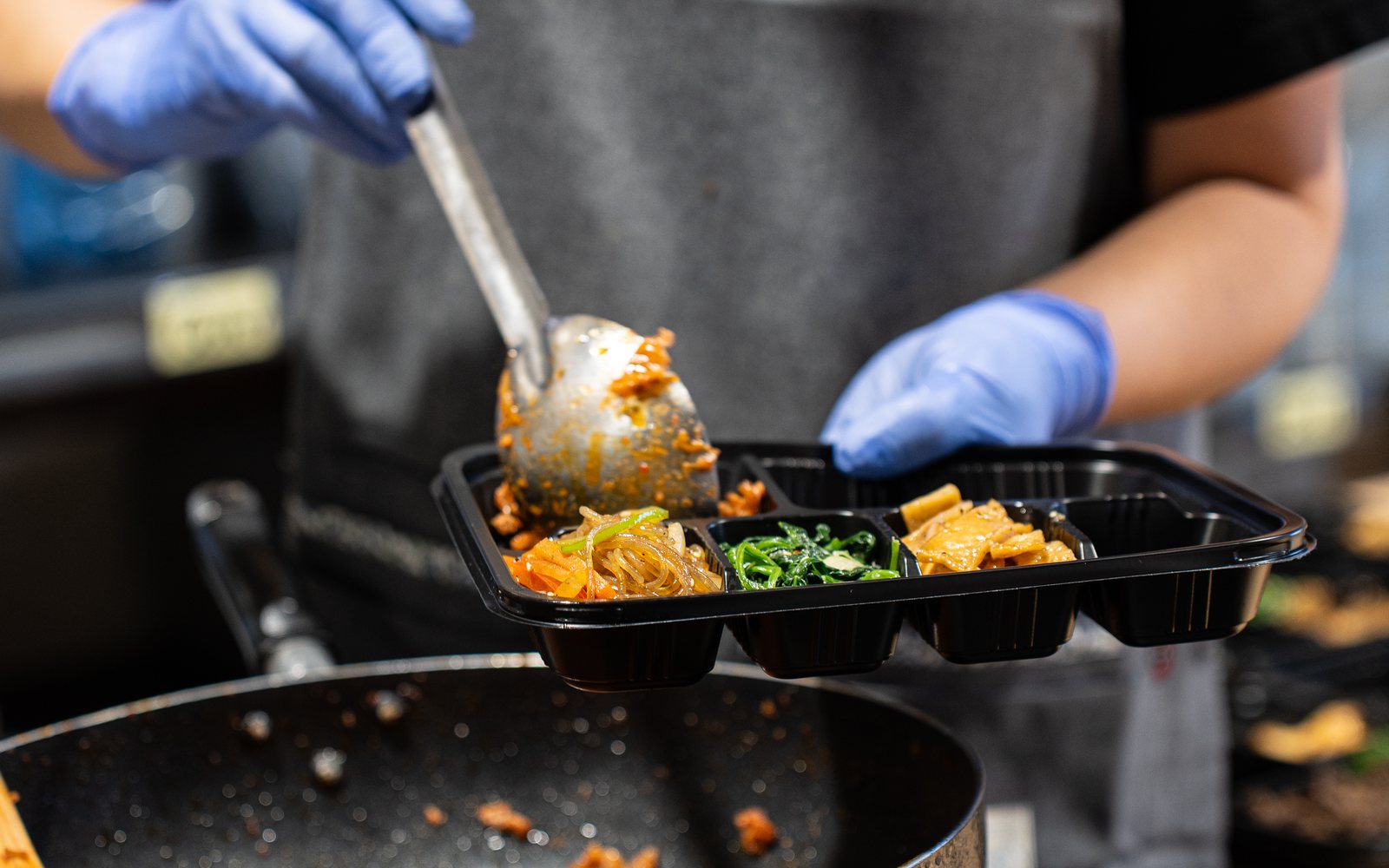 Packing banchan into a partitioned Minari lunch box in our kitchen
