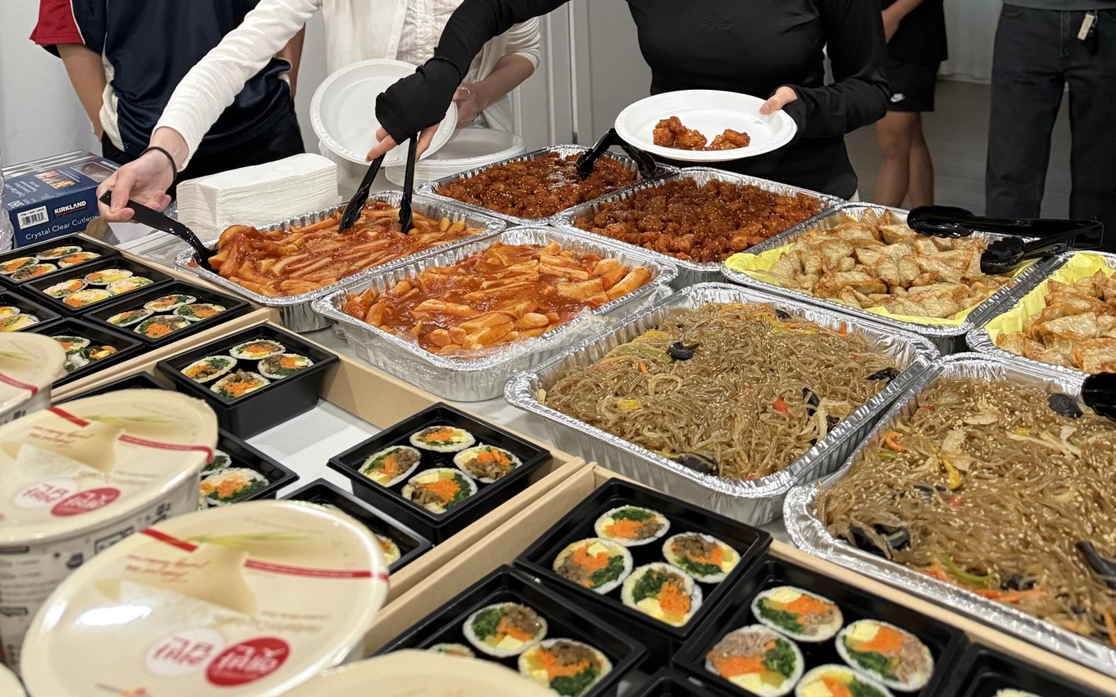 A long line of Minari catering trays and kimbap boxes at a large student event